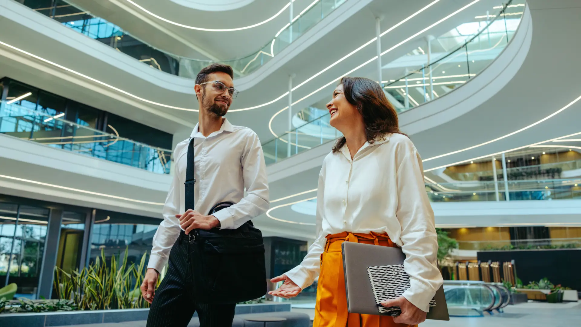 Dois profissionais conversando no átrio iluminado de um edifício corporativo moderno